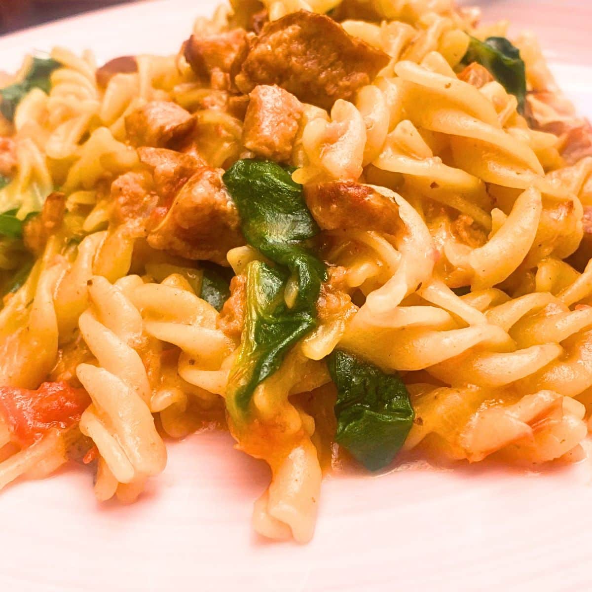 A close up of spinach, sausage and pasta meal.