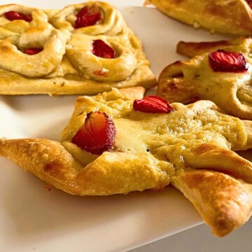 A plate of pastries with strawberries on top.