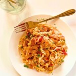 Shrimp and pasta with a fork on a white plate.