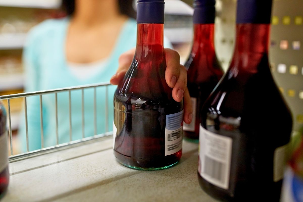 Picture of a woman taking a bottle of vinegar from a shelf.
