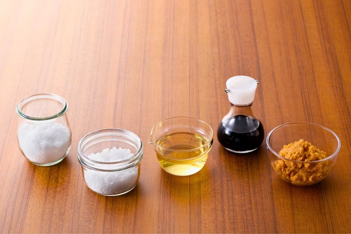 A assortment of cooking condiments in small glass bowls and a jar.
