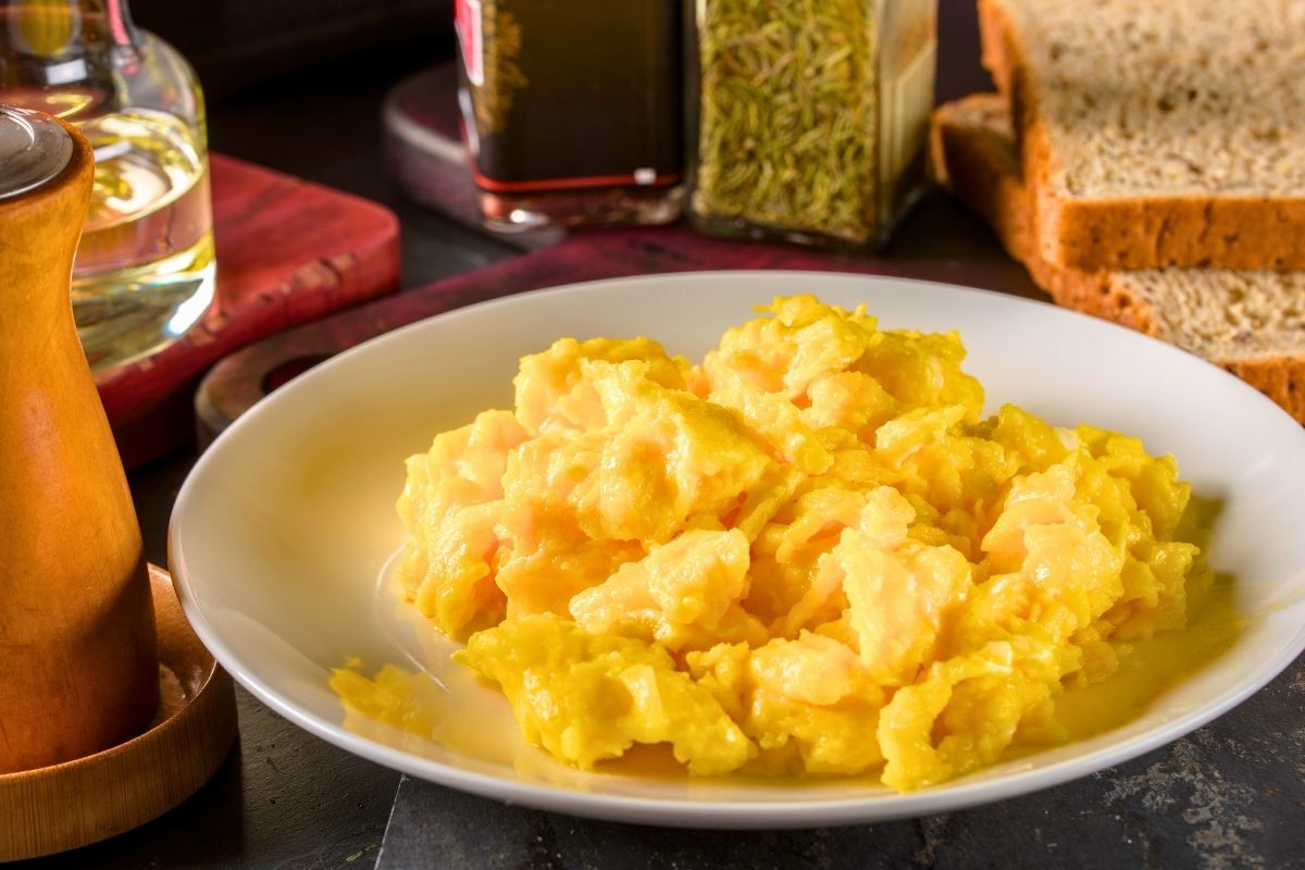 A close up of scrambled eggs on a white plate.
