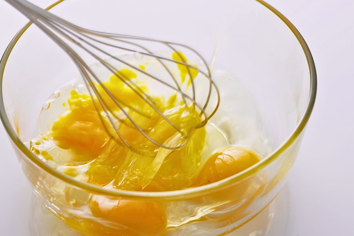 Eggs being stirred in a glass bowl.