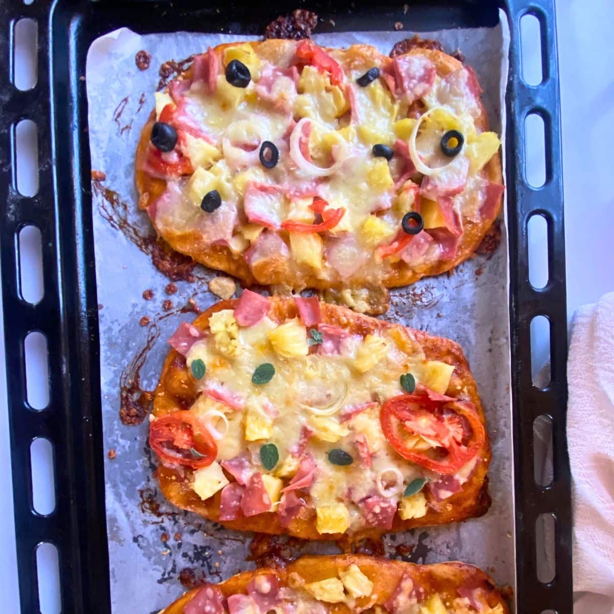A baking tray of three pizzas.