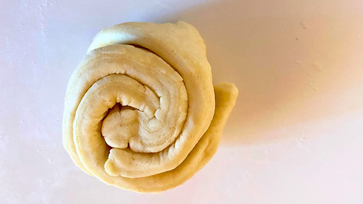 A roll croissant of dough on a white surface.