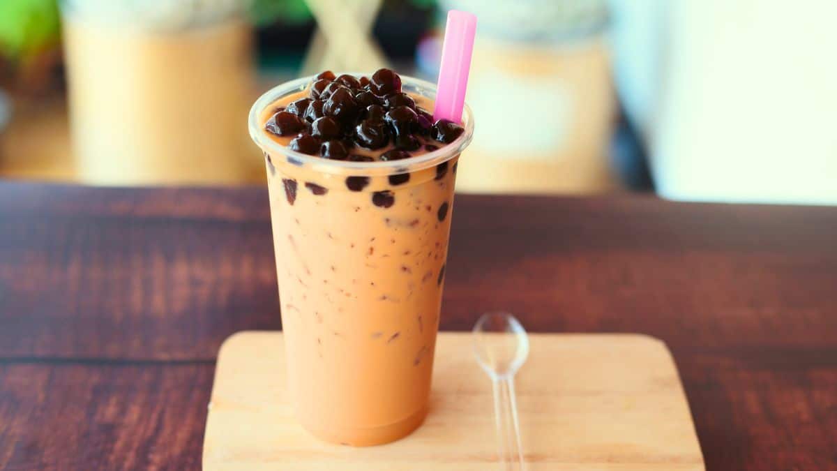 A cup of bubble tea with a straw and a spoon on a table.