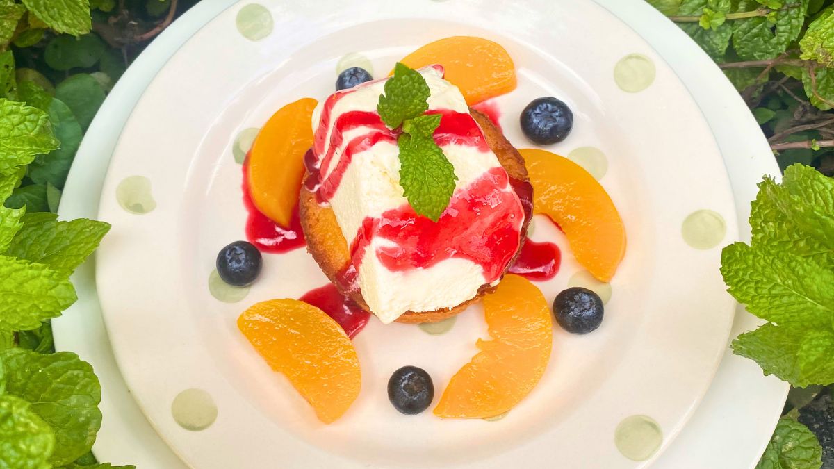 Mastro butter cake on a white plate with cream and fruits within green leaves.
