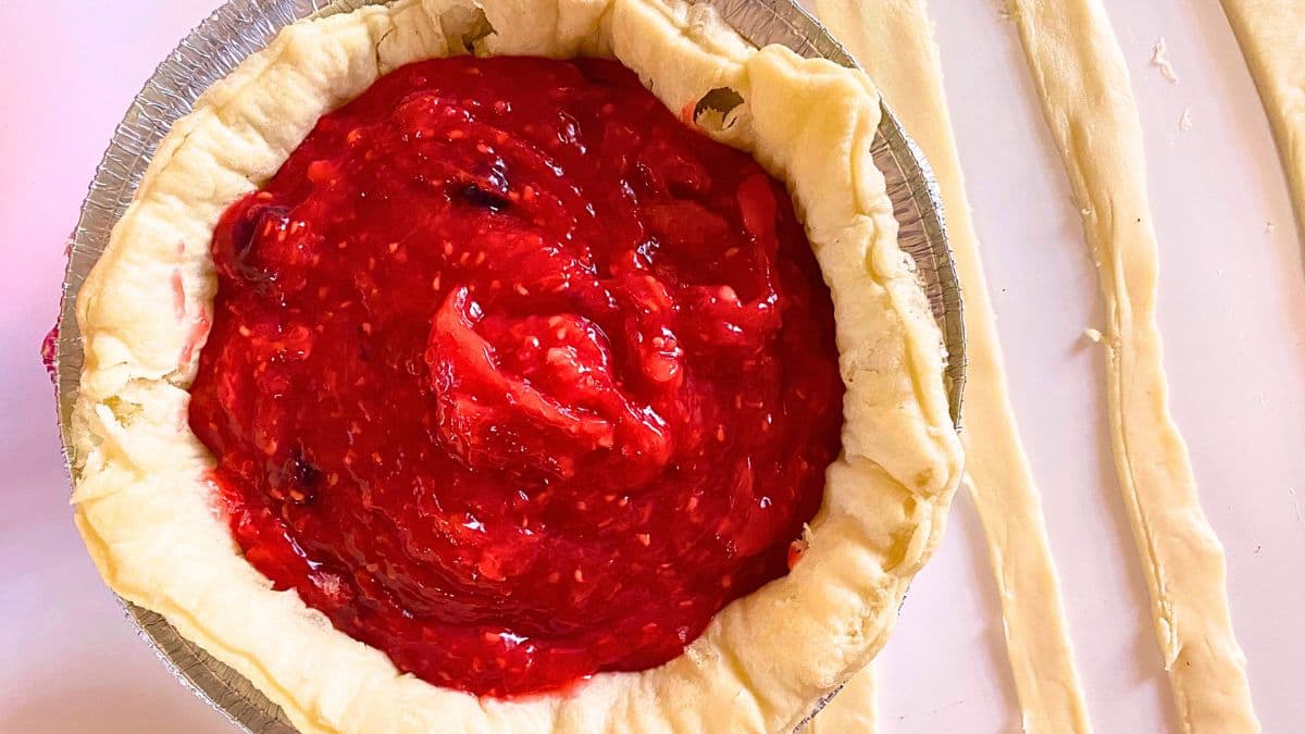 A pie with red strawberry sauce in a pie pan.