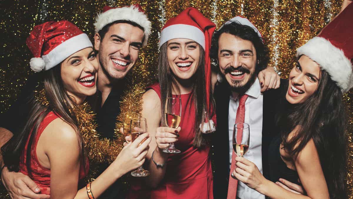 A group of people wearing red Santa hats and smiling.
