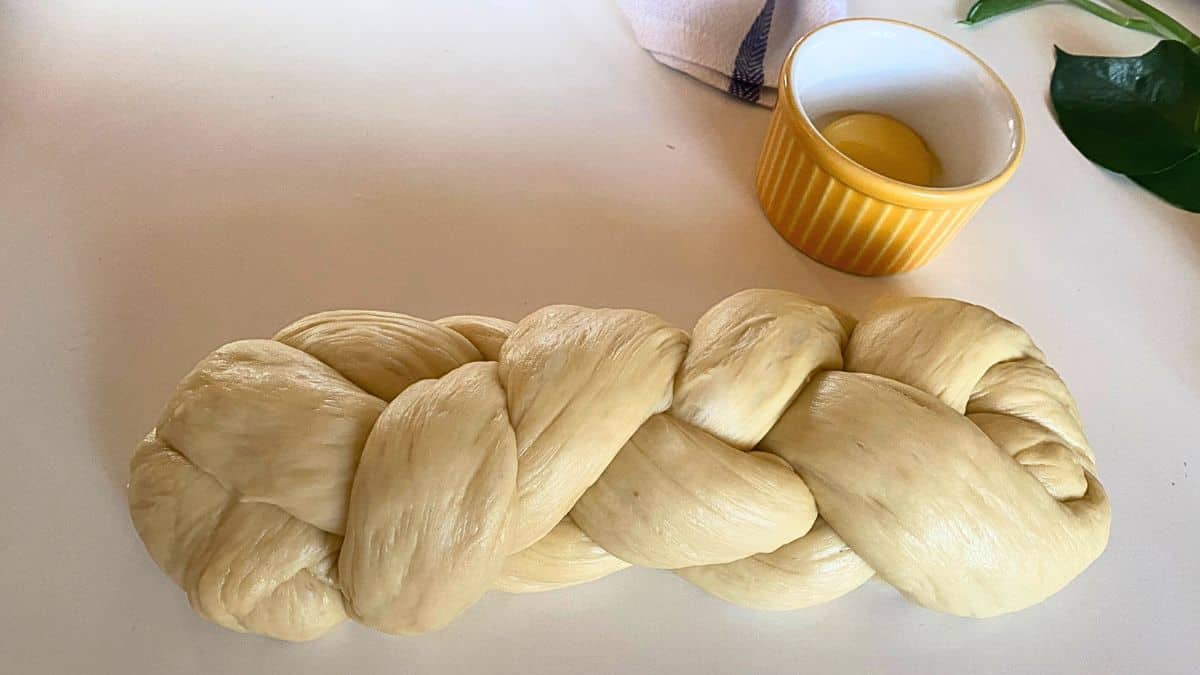 A braided dough next to a bowl of egg,