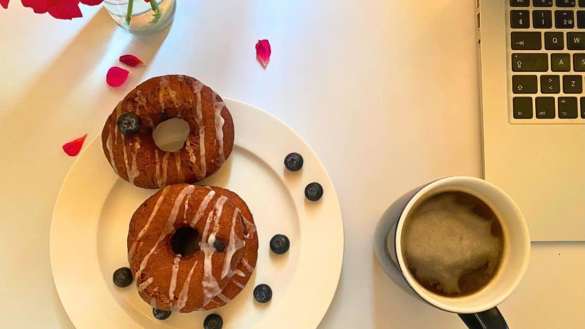 Donuts on a plate next to a cup of coffee.