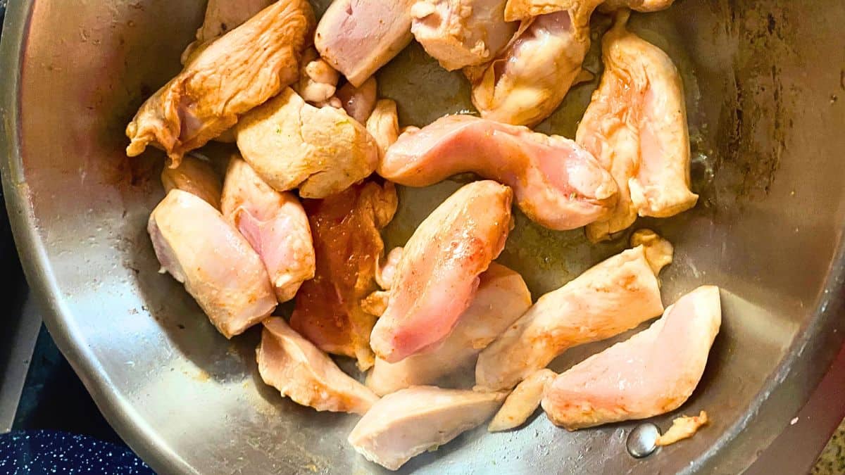 Raw chicken breast pieces in a pan.