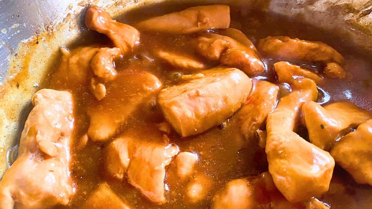 Chicken breasts mixed with teriyaki sauce in a pan.