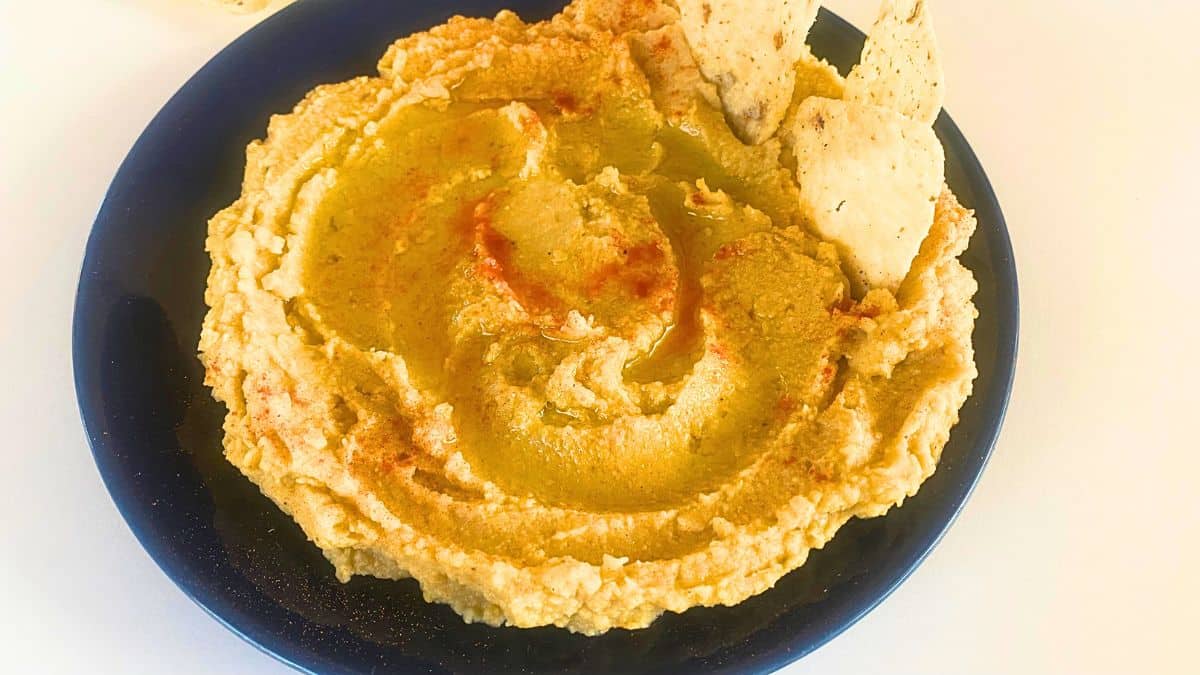 A close up of hummus on a blue plate.