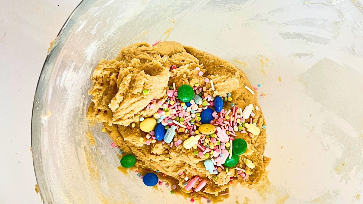 A bowl of cookie mix with candy on it.