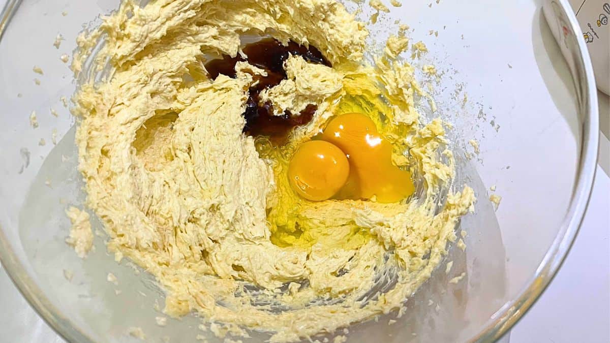 A bowl of dough with eggs and brown liquid.