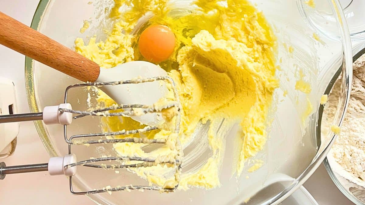 A whisk and egg in a bowl.